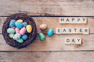 Colorful easter egg in the nest and wood text for Happy Easter Day on wood background with space photo