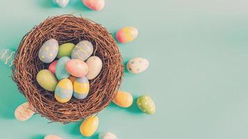 Colorful easter egg and nest on green pastel color background with space. photo