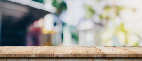 mesa de madera vacía y mesa de luz borrosa en cafetería y café con fondo de bokeh. plantilla de exhibición de productos. foto