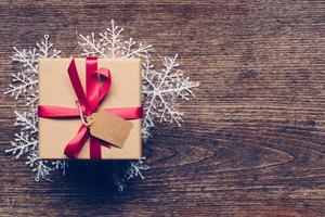 Christmas gift box placed and white snowflakes on wooden planks with space. photo