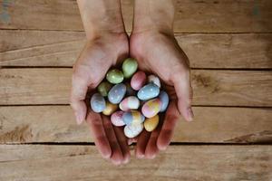 Hand woman holding colorful easter eggs on wood table background. photo