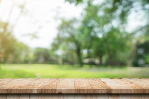 mesa de madera vacía y bokeh desenfocado y fondo borroso de árboles de jardín con luz solar. plantilla de exhibición de productos. foto