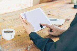 Man using tablet on table in coffee shop with vintage toned filter. photo