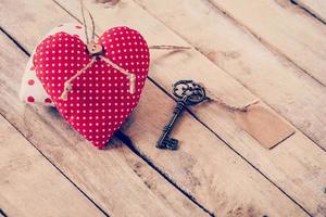Heart fabric and vintage key with tag on wood table background. photo