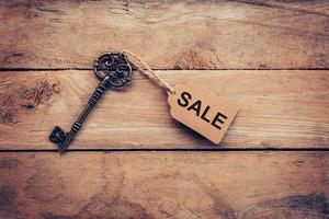 Old key with tag and text sale on wooden photo