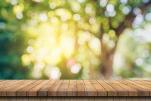 Empty wood table and defocused bokeh and blur background of garden trees with sunlight. product display template. photo