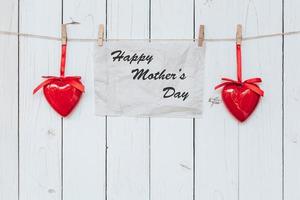 Heart and paper hanging on white wood present, mother's day concept. photo