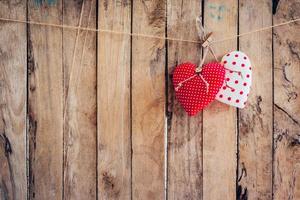 Two heart fabric hanging on clothesline and wood background with space. photo