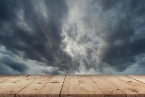 Empty wooden table and dramatic thunder storm clouds at dark sky photo