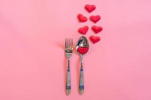 Cutlery set and red heart on pink pastel color with space for text. photo