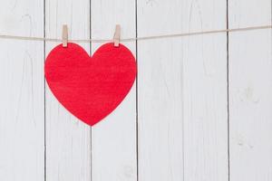 Red heart hanging on white wood  background with copy space. photo