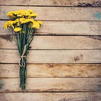 Yellow flowers of bouquet, top view on wooden background texture with copy space photo