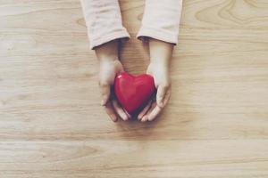 girl hand holding heart on wood table background photo