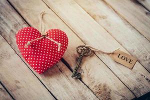 Heart fabric and vintage key with tag label LOVE on wood table background. photo