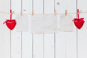 Red heart and old paper blank hanging at clothesline on wood white background with space. Valentine Day. photo