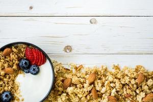 bowl of granola with yogurt, fresh berries, strawberry on wood table with space. photo