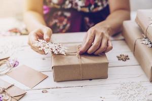 Woman hand making beautiful Christmas gift box at table photo