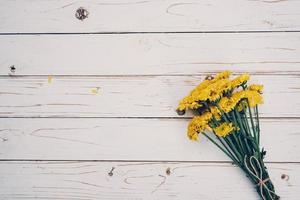 Yellow flowers of bouquet, top view on white wooden background texture with copy space photo