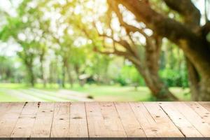 Empty wood table and defocused bokeh and blur background of garden trees in sunlight, display montage for product. photo