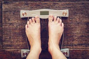 Male on weight scale on wood floor background, Diet concept. photo