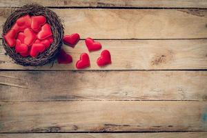 Red heart in the nest on wood background with space photo