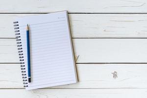 Open notebook with blank pages and pencil on wood table photo