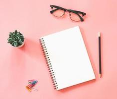 Flat lay mockup design of workspace desk with blank notebook, smartphone, coffee, stationery on pink pastel color with copy space photo