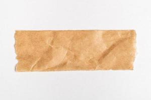 Close up of a ripped piece of brown paper on white background photo