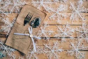 christmas table place setting and silverware, snowflakes on wooden background with space. photo