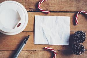 parte superior ver café taza y bolígrafo, blanco papel en madera con Navidad decoración para nuevo año concepto. foto