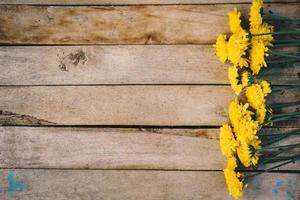 Yellow flowers of bouquet, top view on wooden background texture with copy space photo