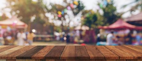 vacío madera mesa y desenfocado bokeh y difuminar antecedentes de jardín arboles en luz de sol, monitor montaje para producto. foto