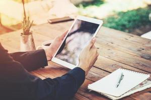 Asia business man holding tablet on table in coffee shop with vintage toned filter. photo