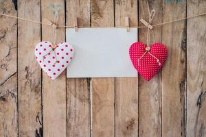 Two heart fabric and paper hanging on clothesline at wood background with space. photo