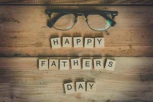 Happy father's day block with glasses on wood background. photo