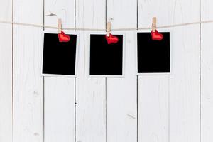 Three photo frame blank and red heart hanging on white wood background with space