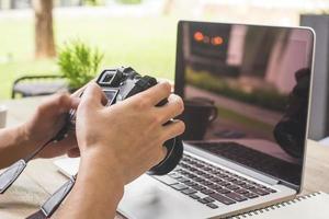 hombre mano participación cámara y utilizando ordenador portátil computadora en café tienda. foto