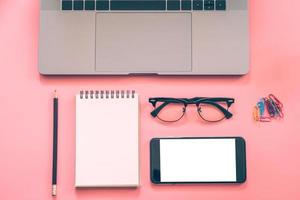 Flat lay design of workspace desk with laptop, blank notebook, smartphone, pencil, stationery with copy space background photo