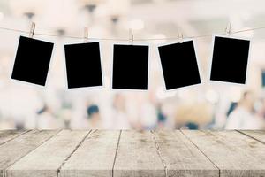 Empty wood table and instant photo hanging on blur image background of people display montage for product.