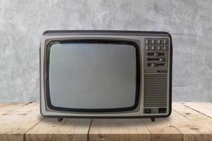 Vintage television on wooden table and cement wall texture and background. photo