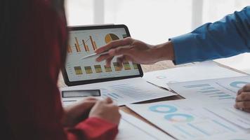 Financial analysts analyze business financial reports on a digital tablet planning investment project during a discussion at a meeting of corporate showing the results of their successful teamwork. video