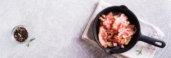 Crispy strips of bacon fried in a pan on the table. Top  view. Web banner photo