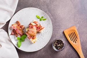 Mashed potatoes wrapped in fried bacon on a plate on the table. Top view photo