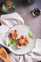 Rolls of fried bacon and mashed potatoes and basil on a plate on the table. Top and vertical view photo