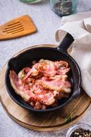 Crispy strips of bacon fried in a pan on the table. Vertical view photo