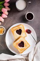 brindis con un corazón lleno con frambuesa mermelada en un lámina. desayuno para un Pareja. parte superior y vertical foto