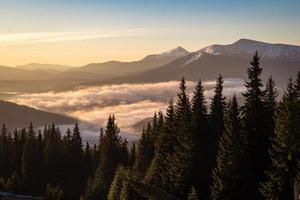 Over clouds view on snow capped mountain ranges landscape photo