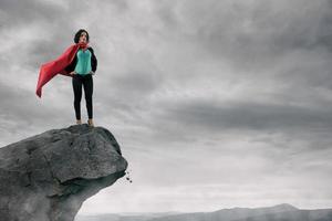 Business woman as a super hero on the peak of a mountain photo