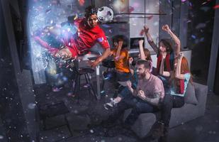 Group of friends watch a football match on television with a soccer player who exits from screen photo