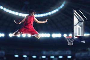 Acrobatic slam dunk of a basket player in the basket at the stadium photo